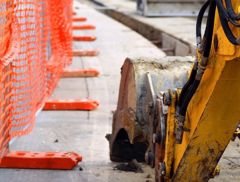 Excavator bucket at a construction site with safety fencing